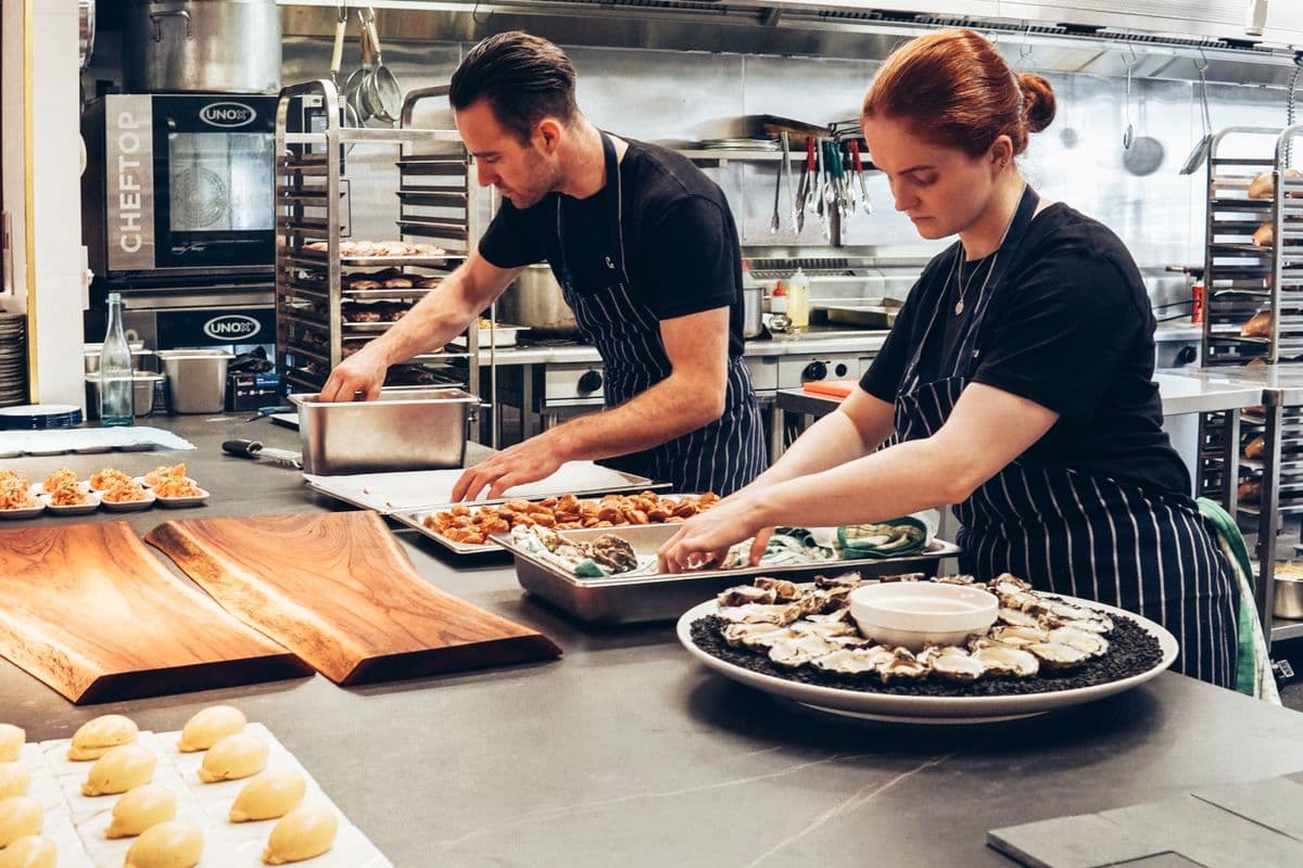 Chefs plating and packing food in a commercial production kitchen